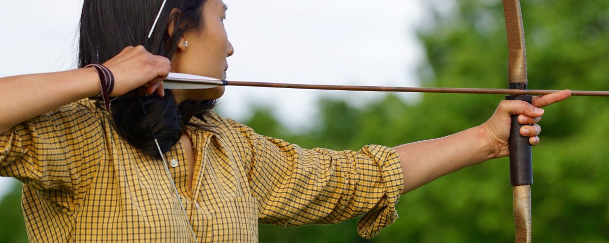 Female archer drawing back bow